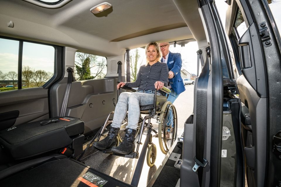 A support worker assisting a woman in a wheelchair inside a spacious wheelchair-accessible van.