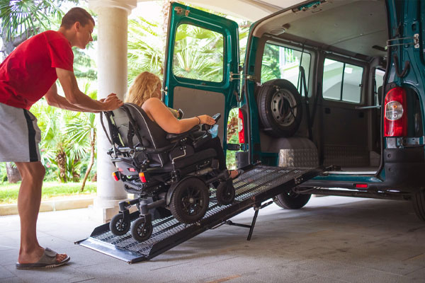 A passenger in a wheelchair boarding an accessible van via the fold-out ramp.