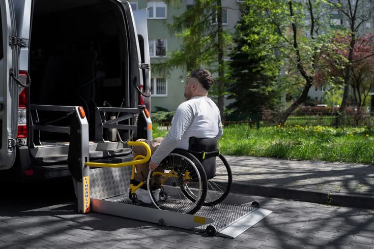 A passenger in a wheelchair boarding an accessible taxi van using the rear powered lift.